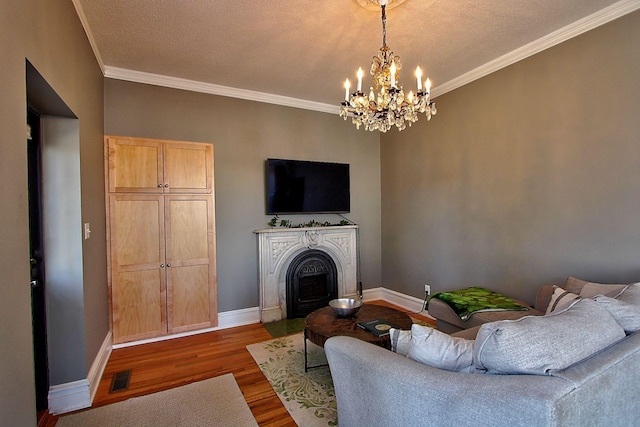 living room with a textured ceiling, wood-type flooring, ornamental molding, and an inviting chandelier