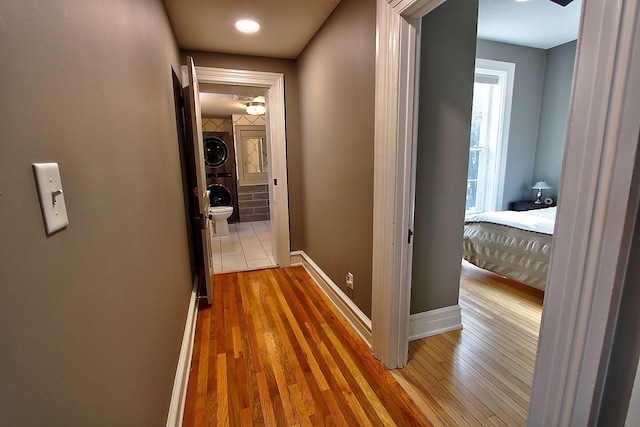 hallway featuring stacked washer and dryer and hardwood / wood-style floors