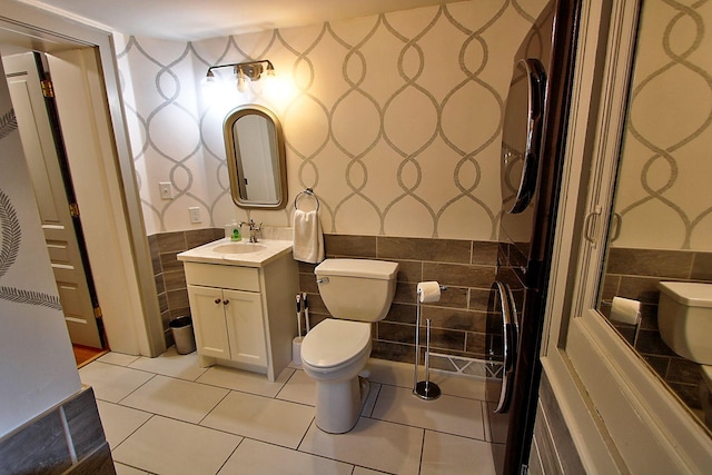 bathroom with tile patterned flooring, vanity, tile walls, and toilet