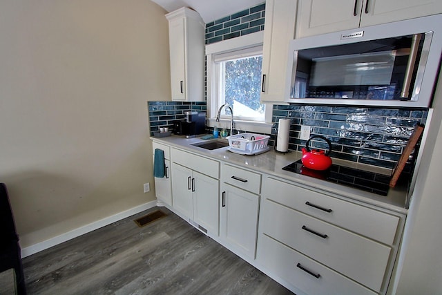 kitchen with backsplash, white cabinetry, sink, and dark wood-type flooring