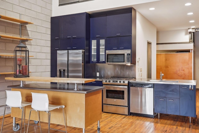 kitchen with decorative backsplash, appliances with stainless steel finishes, a kitchen breakfast bar, blue cabinets, and a kitchen island