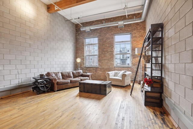 living room with wood-type flooring, a high ceiling, and brick wall