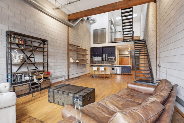 living room with beamed ceiling, wood-type flooring, and a high ceiling