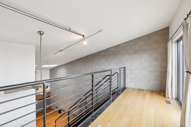 hallway with hardwood / wood-style floors and vaulted ceiling