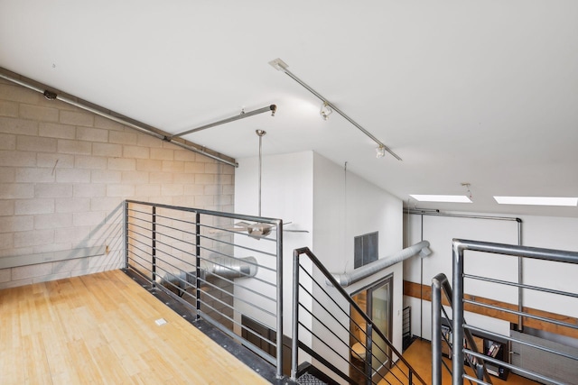 hallway with hardwood / wood-style floors, a skylight, and track lighting