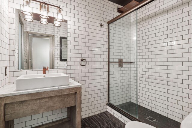 bathroom featuring vanity, a shower with door, tile patterned flooring, toilet, and tile walls