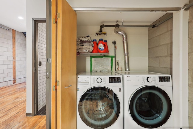 clothes washing area featuring washing machine and clothes dryer and light wood-type flooring