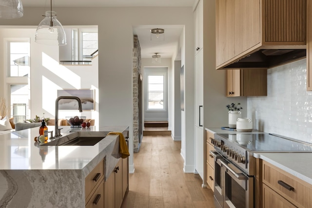 kitchen featuring plenty of natural light, double oven range, sink, decorative light fixtures, and light hardwood / wood-style floors