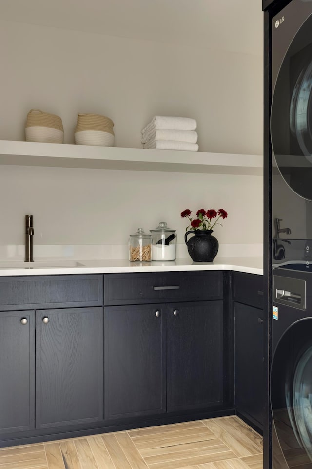 clothes washing area featuring cabinets, stacked washer / drying machine, and sink