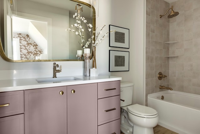 full bathroom featuring vanity, hardwood / wood-style floors, tiled shower / bath combo, and toilet