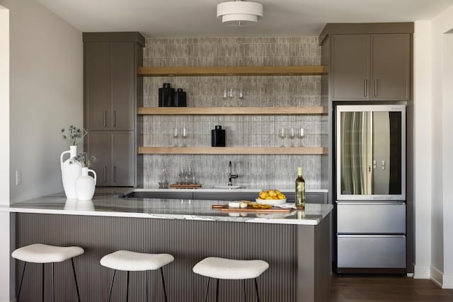 bar with gray cabinetry, stainless steel fridge, and dark hardwood / wood-style floors