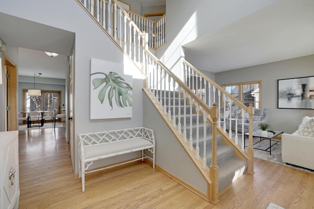 stairs featuring a healthy amount of sunlight, baseboards, and wood finished floors