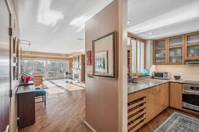 kitchen with cooktop, oven, light hardwood / wood-style floors, and ventilation hood