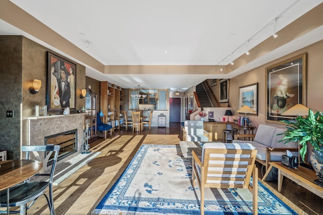 living room featuring a premium fireplace, rail lighting, and wood-type flooring