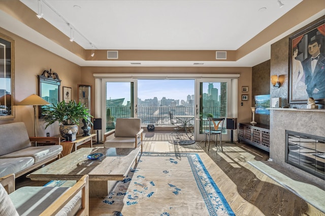 living room with a premium fireplace, rail lighting, and hardwood / wood-style flooring