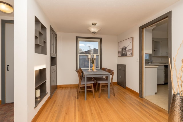 dining room featuring light wood finished floors and baseboards