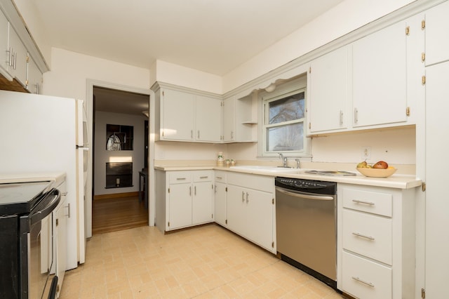 kitchen featuring black electric range, light countertops, stainless steel dishwasher, white cabinets, and a sink