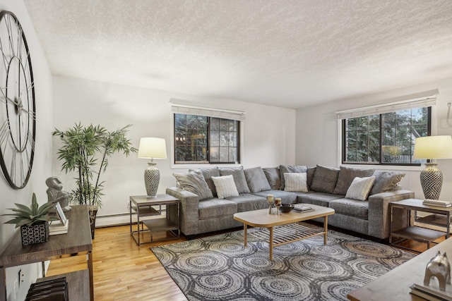 living room with a textured ceiling, light hardwood / wood-style floors, and a baseboard heating unit