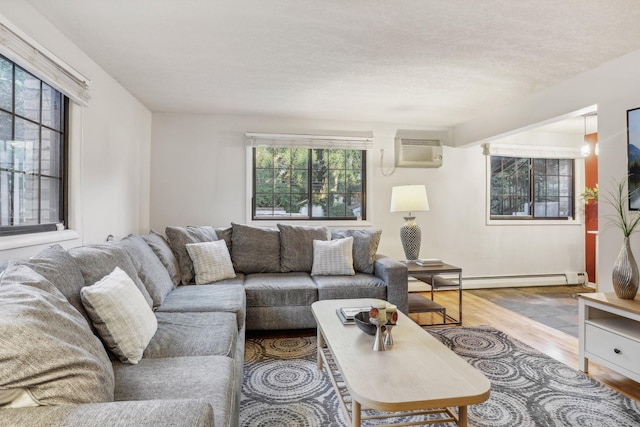 living room featuring a wall mounted AC, plenty of natural light, a baseboard radiator, and hardwood / wood-style flooring