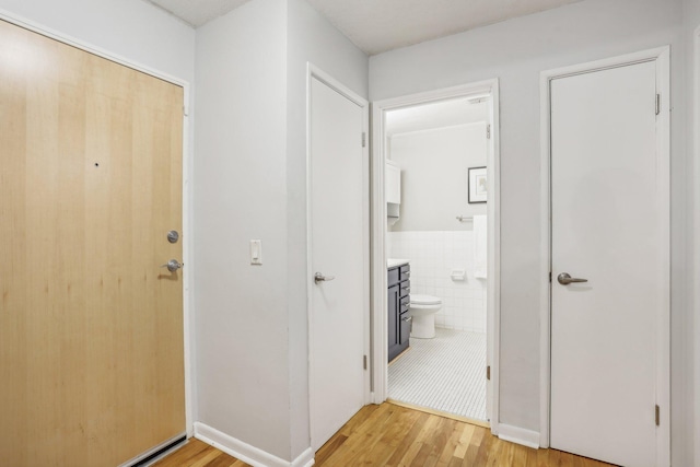 hall with light hardwood / wood-style flooring and tile walls