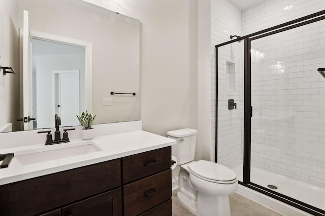 bathroom featuring tile patterned flooring, vanity, toilet, and a shower with shower door