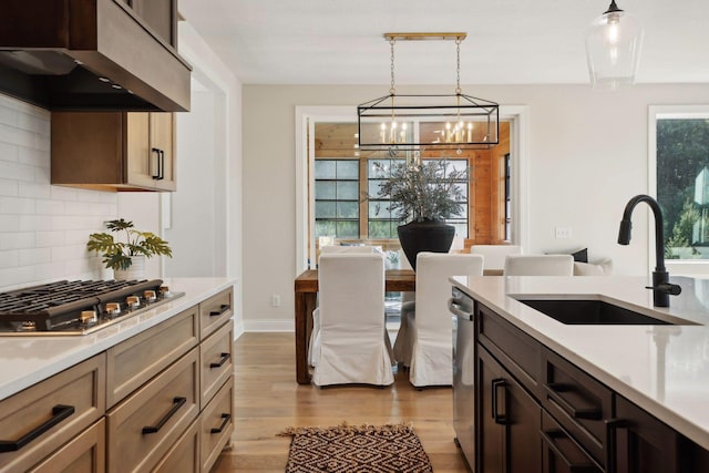 kitchen with sink, premium range hood, stainless steel appliances, tasteful backsplash, and decorative light fixtures