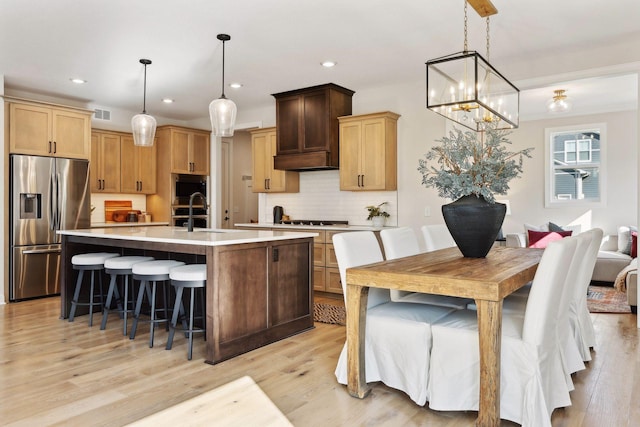 kitchen with stainless steel appliances, hanging light fixtures, a kitchen island with sink, and sink