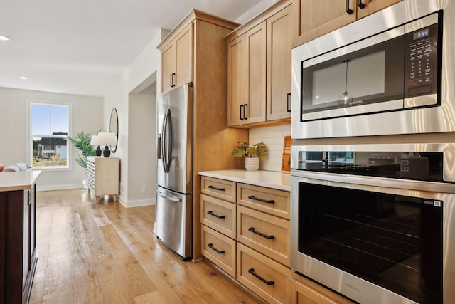 kitchen featuring appliances with stainless steel finishes, light brown cabinetry, light hardwood / wood-style floors, and decorative backsplash