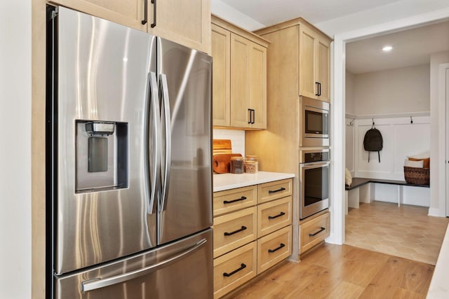 kitchen featuring backsplash, stainless steel appliances, light hardwood / wood-style floors, and light brown cabinets