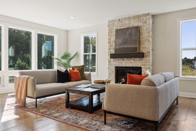 living room with dark hardwood / wood-style flooring and a stone fireplace