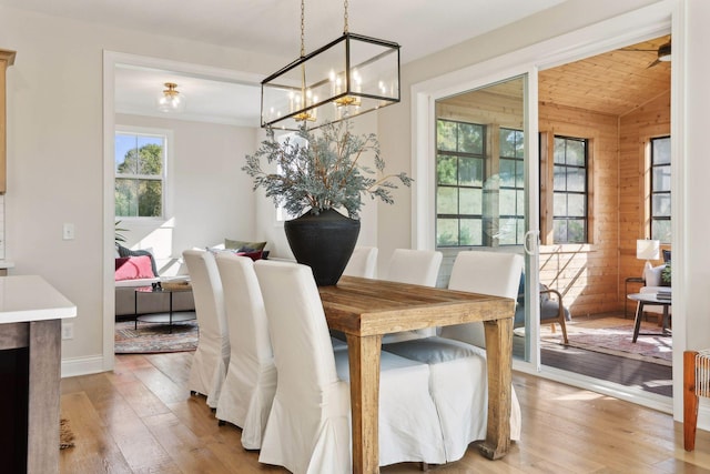 dining space featuring lofted ceiling, light wood-type flooring, and wood walls