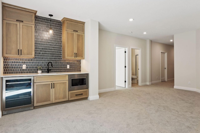 kitchen featuring stainless steel microwave, sink, wine cooler, hanging light fixtures, and light colored carpet