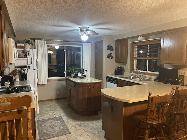 kitchen with a textured ceiling, kitchen peninsula, sink, and white appliances