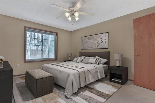 bedroom with ceiling fan, light colored carpet, and a textured ceiling