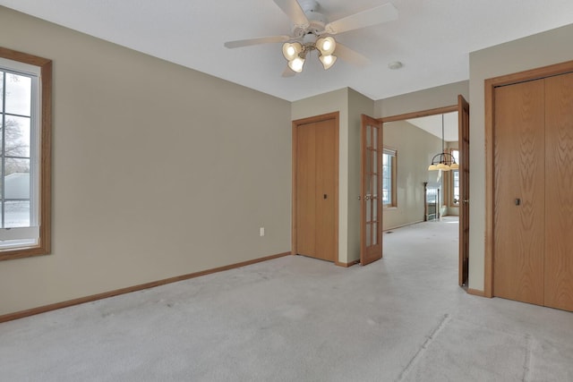 carpeted spare room with ceiling fan with notable chandelier