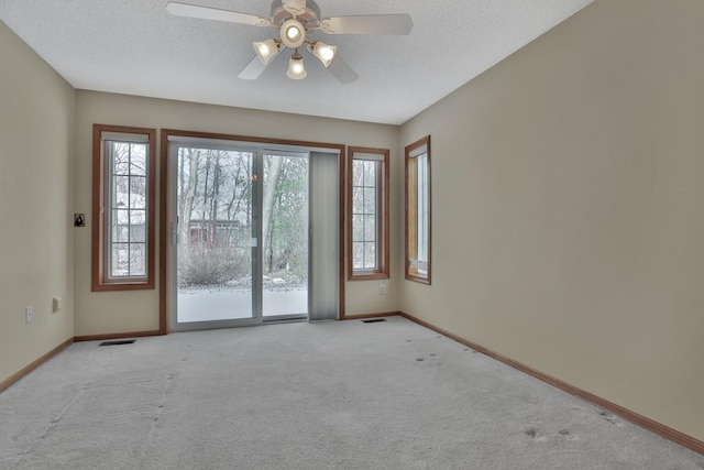 carpeted spare room with a textured ceiling and ceiling fan