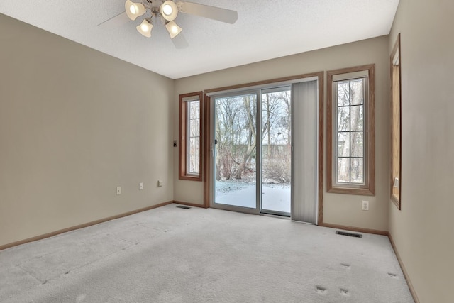 carpeted spare room with a textured ceiling and ceiling fan