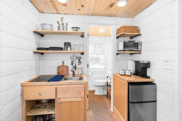 interior space featuring hardwood / wood-style flooring, wood walls, wooden ceiling, and fridge