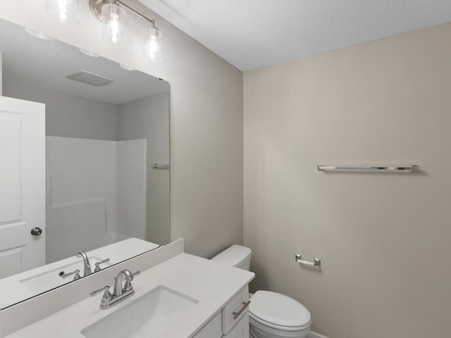 bathroom with toilet, vanity, a textured ceiling, and walk in shower