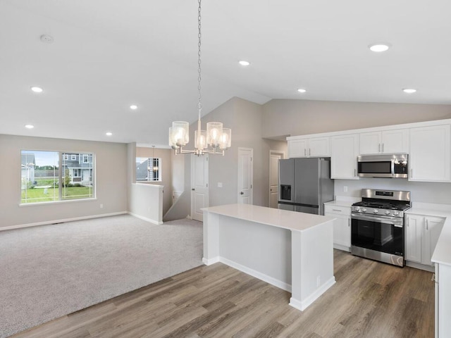 kitchen with decorative light fixtures, stainless steel appliances, an inviting chandelier, white cabinets, and wood-type flooring