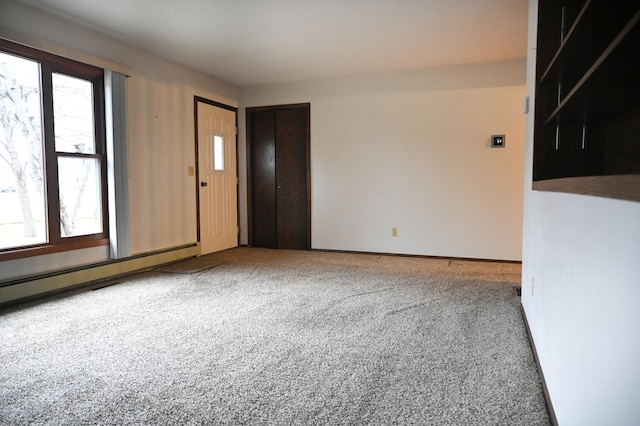 carpeted spare room featuring a baseboard heating unit