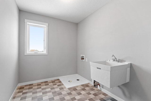 washroom with hookup for a washing machine, a textured ceiling, and sink