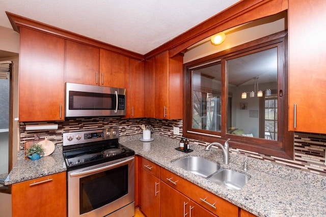 kitchen featuring tasteful backsplash, sink, stainless steel appliances, and light stone countertops