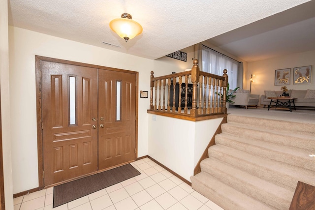 entryway with light tile patterned flooring and a textured ceiling