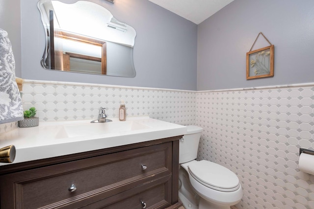 bathroom with vanity, tile walls, and toilet