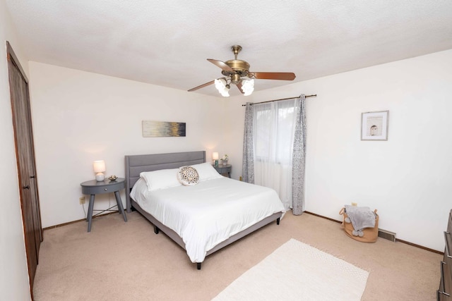 carpeted bedroom with ceiling fan and a textured ceiling