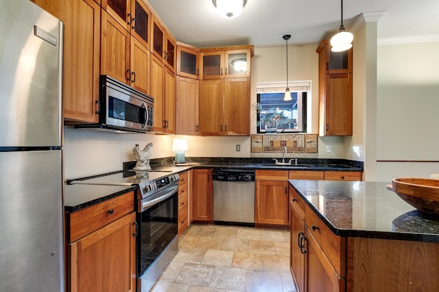 kitchen with ornamental molding, stainless steel appliances, sink, pendant lighting, and dark stone countertops