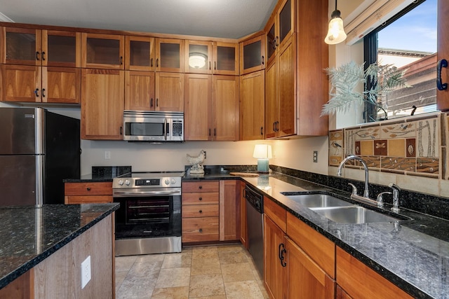 kitchen featuring sink, stainless steel appliances, hanging light fixtures, and dark stone counters