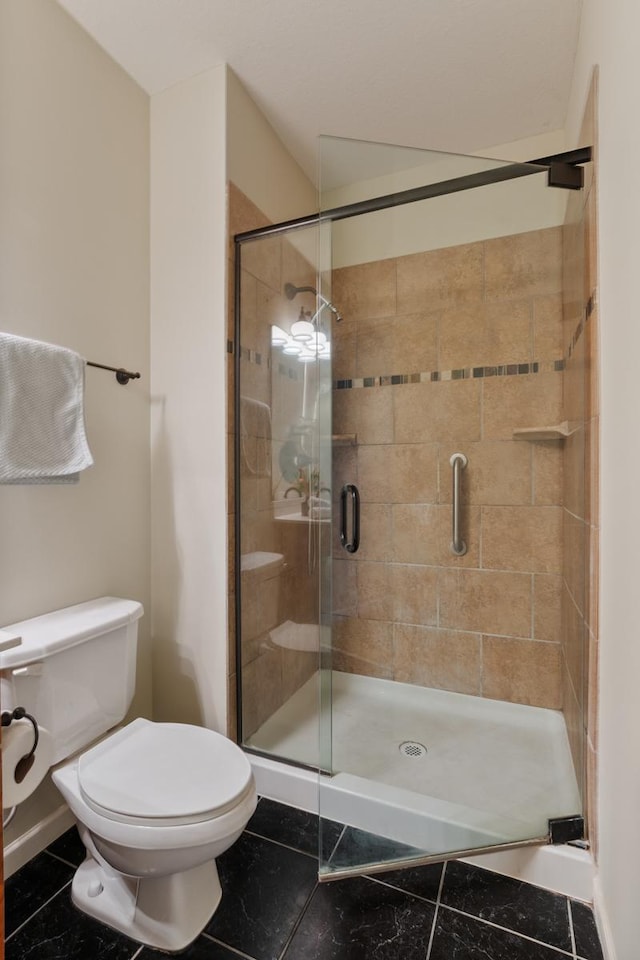 bathroom featuring tile patterned floors, toilet, and a shower with shower door