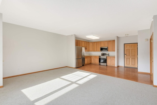 kitchen featuring light brown cabinets, light colored carpet, and appliances with stainless steel finishes